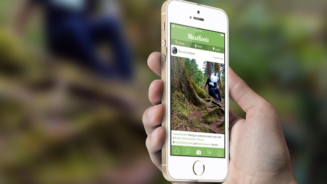 Hand holding a smartphone displaying an outdoor activity app with a photo of a person hiking on a forest trail.