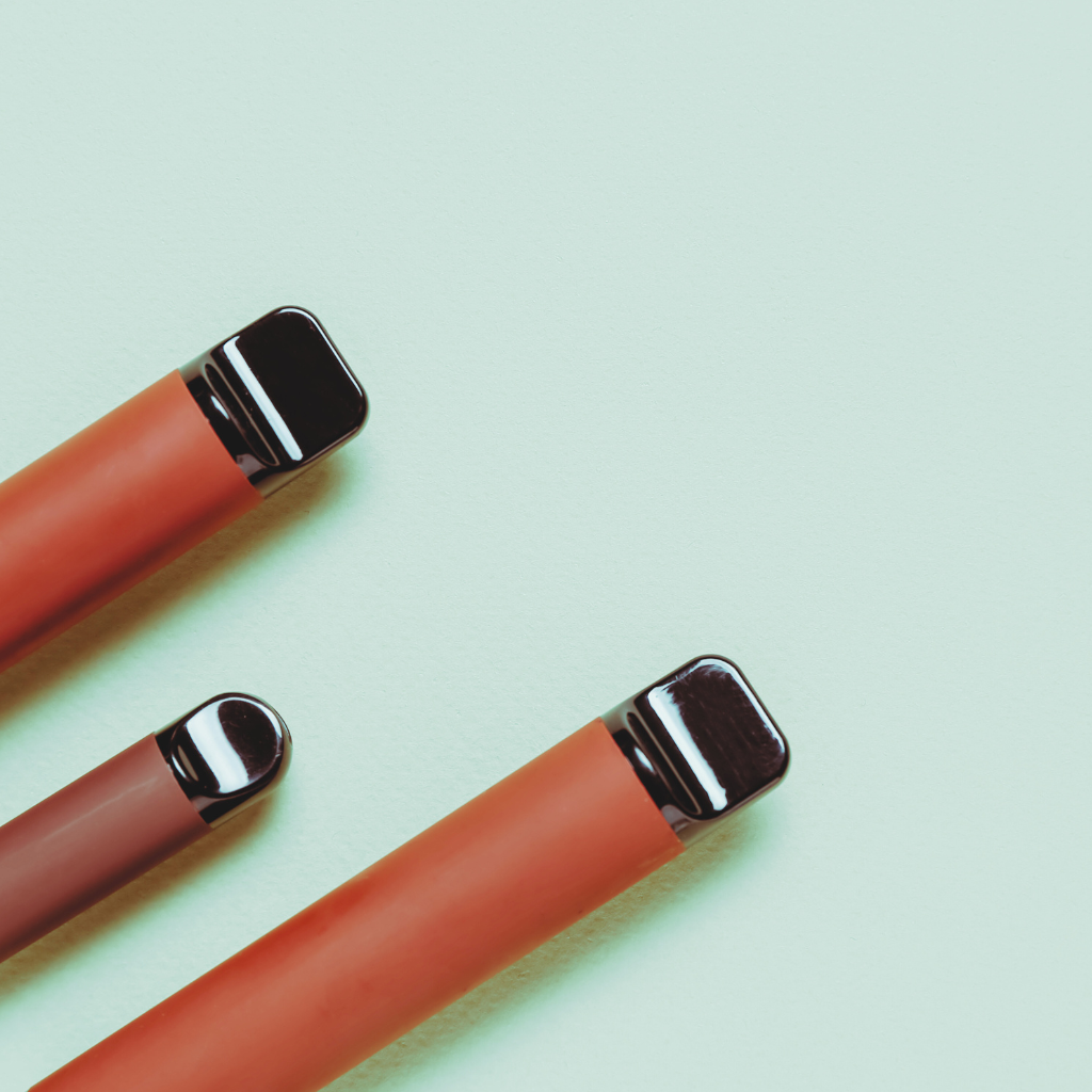 Close-up of three sleek vape pens with metallic mouthpieces on a light background