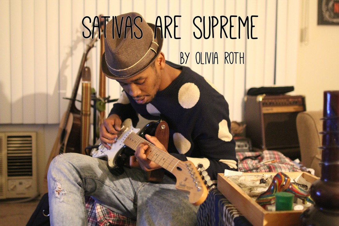 A man in a fedora playing an electric guitar next to a wooden tray containing smoking accessories, with the text SATIVAS ARE SUPREME overlaid